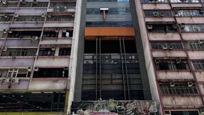 A multi-story building with numerous air conditioning units, a prominent 'T' logo, and a large advertisement banner. - Hennessy Hotel (Hong Kong)