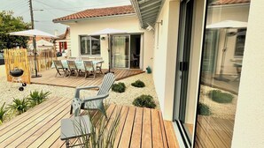 Un patio con mesa y sillas, una parrilla de barbacoa y una terraza de madera.