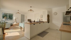 Una cocina moderna con una isla central, iluminación colgante y vistas al exterior.
