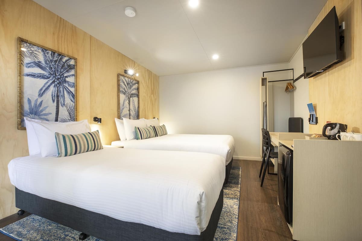 Habitación de hotel con dos camas, un escritorio y un televisor.