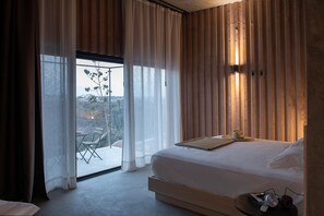 Un dormitorio con una cama grande, vistas por la ventana y una mesa con una planta.
