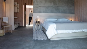 A modern bedroom with a large bed, a wooden wardrobe, and a concrete ceiling. - Casa Santos (Todos Santos)