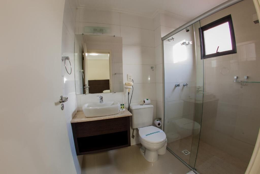 Un baño moderno con cabina de ducha de vidrio, un lavabo blanco y un inodoro.