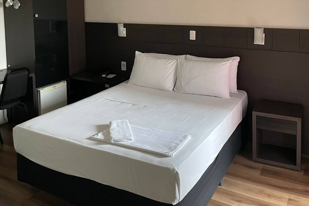 Una habitación de hotel moderna con una cama grande, un escritorio y una silla.