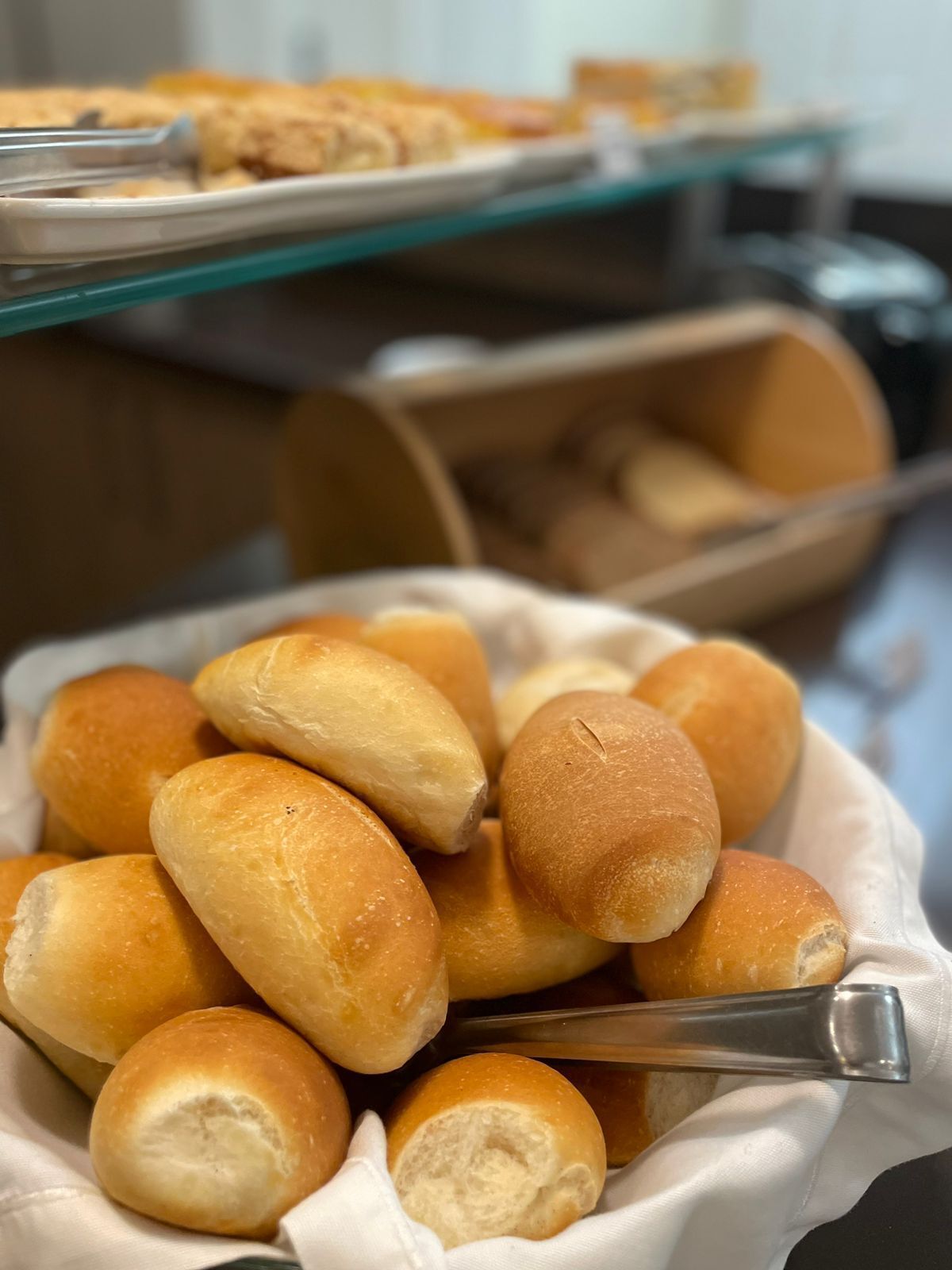 Un bollo recién horneado, una bandeja de pasteles y un recipiente de madera en un ambiente de cocina.