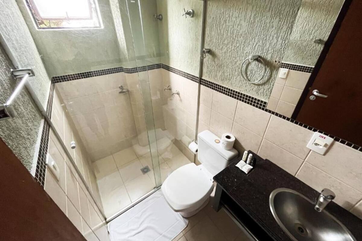 Un baño con ducha de vidrio, inodoro y lavamanos.