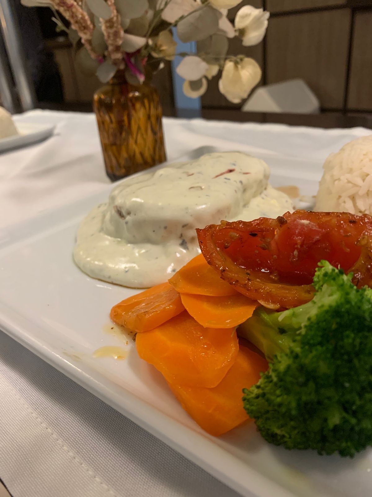 A plate with a creamy sauce, rice, carrots, and broccoli.