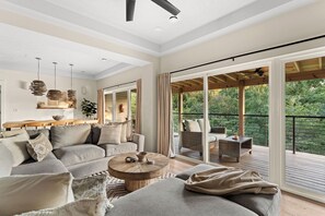 A spacious living area with a sofa, coffee table, and a balcony with wicker furniture.