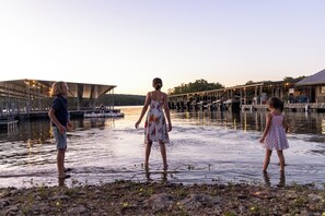 A waterfront scene with a dock and boats, a bridge, and a building with a metal roof. - Maia House – Luxury Waterfront Retreat w/ Resort Amenities (Branson)