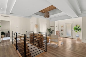 Un interior amplio con una escalera de madera, un colgante de luz y vistas al exterior.