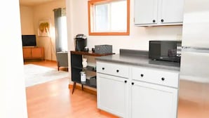 Una cocina con armarios blancos, microondas y cafetera.