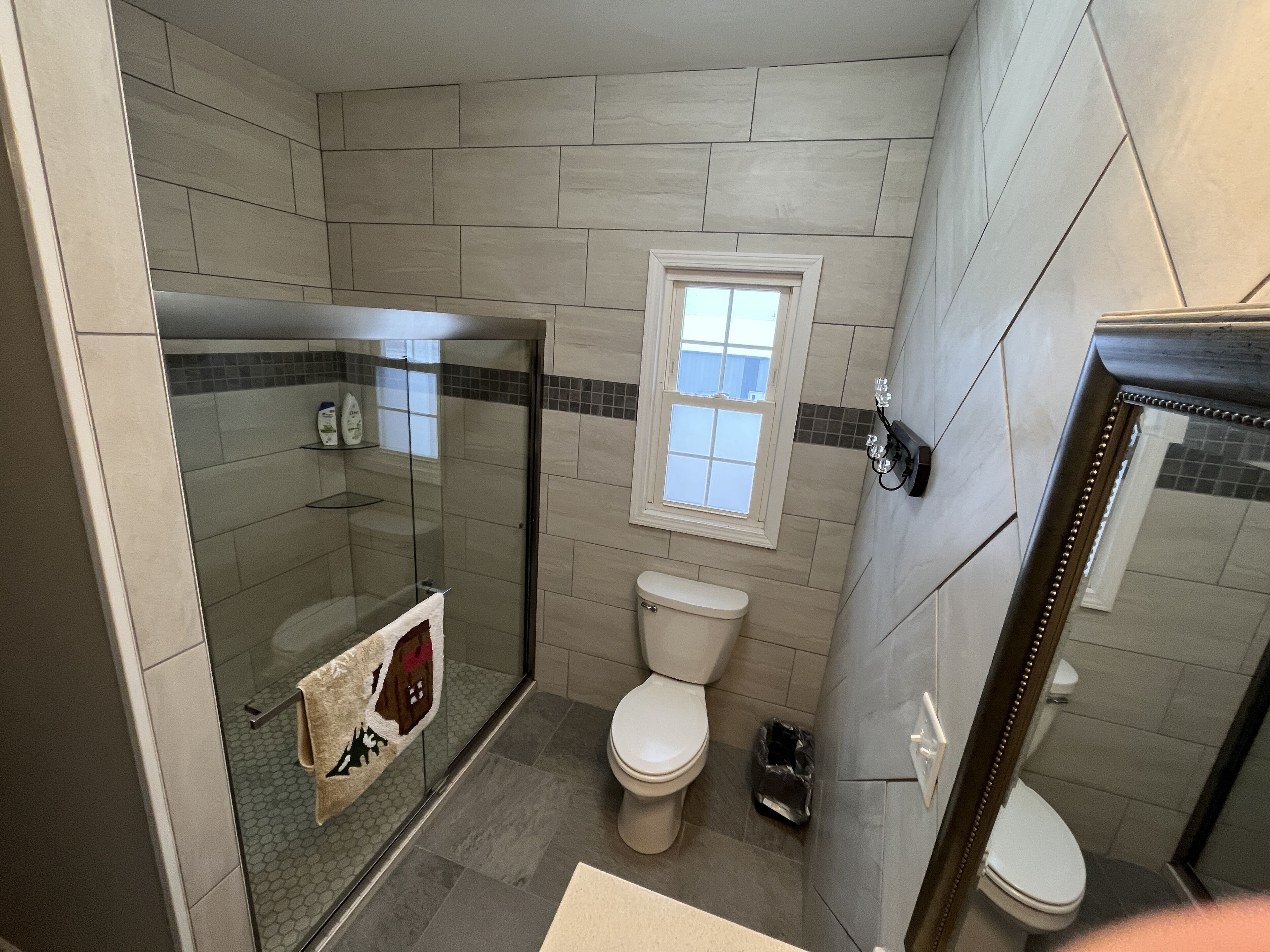 Ein Badezimmer mit Duschkabine, Toilette und Fenster.