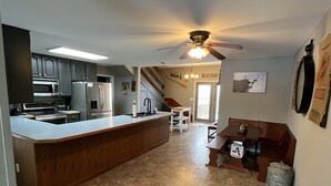 Een moderne keuken met een centraal eiland, roestvrijstalen apparatuur en een plafondventilator.