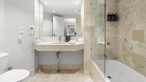 A modern bathroom with a glass-enclosed shower, a white toilet, and a marble-tiled vanity. - Serain Residences on View  (Surfers Paradise)