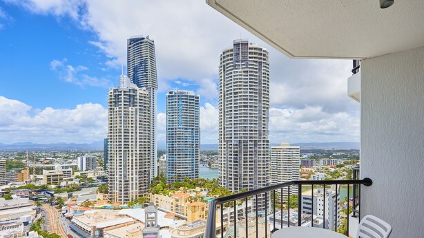 A balcony with a table and chairs, overlooking a cityscape with tall buildings and a body of water. - Serain Residences on View  (Surfers Paradise)