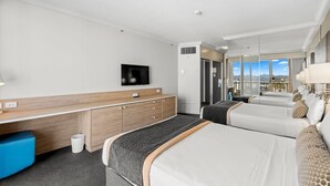 A hotel room with a bed, a desk, a TV, and a view of the city. - Serain Residences on View  (Surfers Paradise)