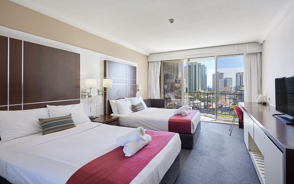 A hotel room with two beds, a balcony with a city view, a desk with a TV, and a window with curtains. - Serain Residences on View (Surfers Paradise)