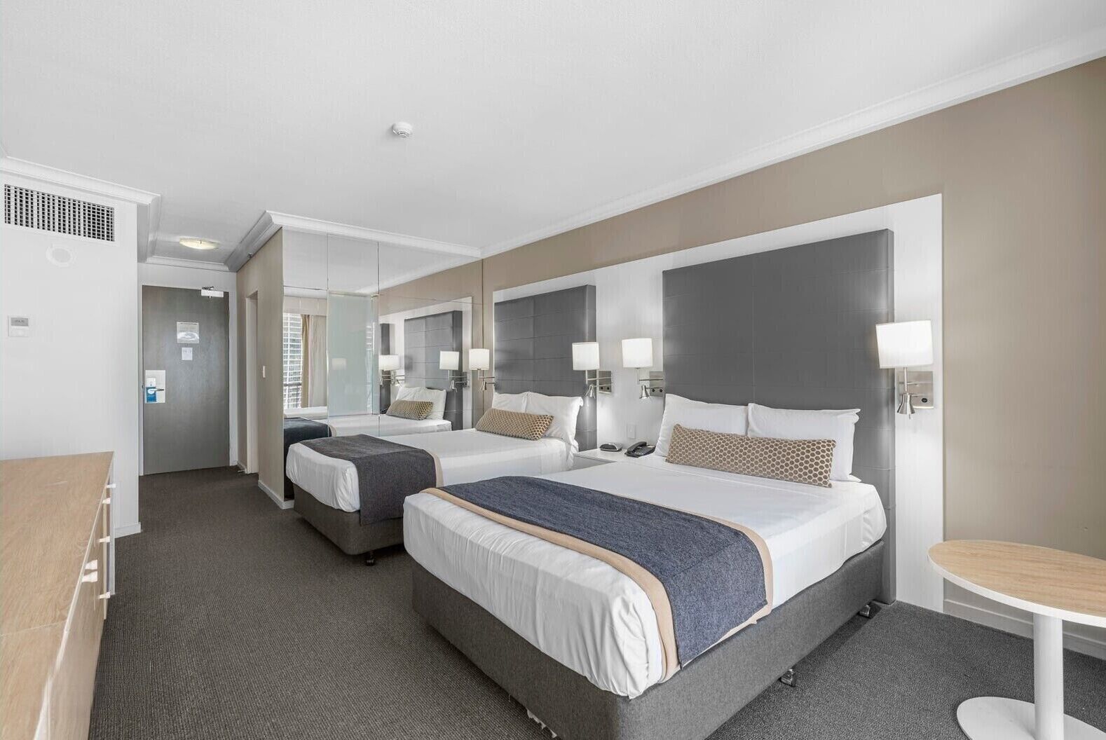 Una habitación de hotel con dos camas, un escritorio y una mesita.
