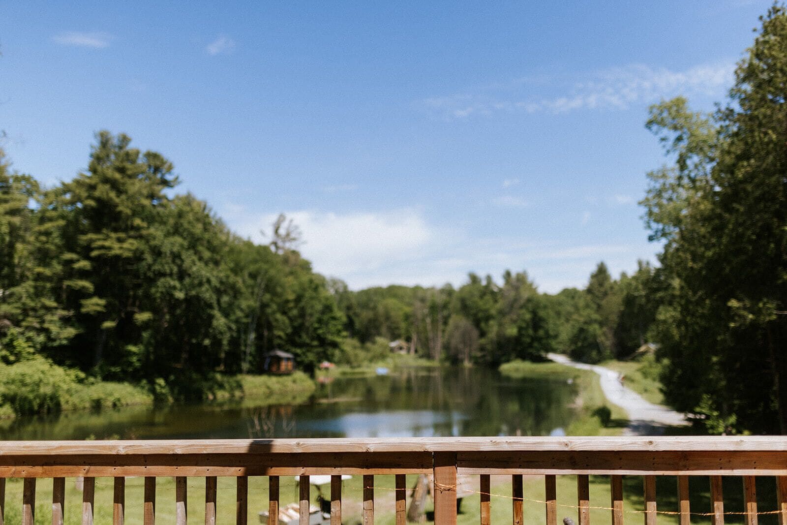 A wooden deck overlooking a calm lake surrounded by dense forest.
