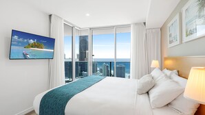 A modern hotel room with a large bed, a city view, a television, and a balcony with curtains. - H Residences Ocean View (Surfers Paradise)