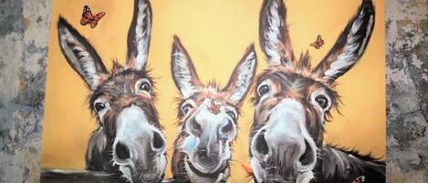 A painting of three donkeys on a branch with butterflies.