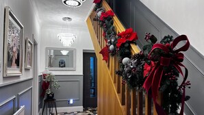 A staircase with a wooden handrail, decorated with red bows and greenery. - Build your memories, hot tub, garden, sleeps 14 (Porthcawl)