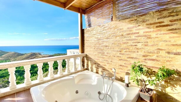 A balcony with a hot tub, a potted plant, and a view of the sea. - Inviting 2-Bed Apartment in Cofresi (Cofresi, Puerto Plata)