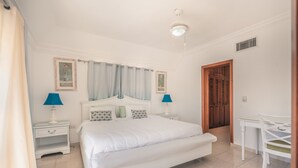 Un dormitorio con una cama grande, dos mesitas de noche con lámparas, un escritorio y una silla.