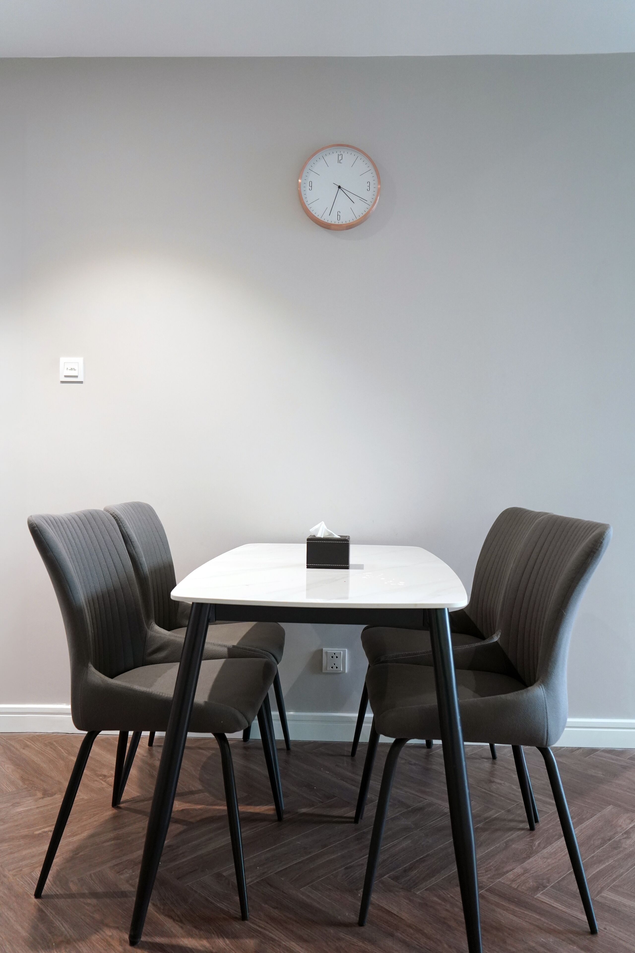 Un salón de conferencias con una mesa redonda, cuatro sillas y un reloj en la pared.