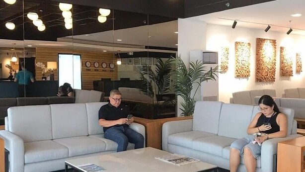 A modern interior with two sofas, a coffee table, and a reception area in the background. - Fynn Boutique Hotel (Bacoor City)
