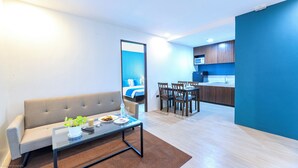 A modern living room with a sofa, coffee table, and a dining area with chairs and a table. - Fynn Boutique Hotel (Bacoor City)