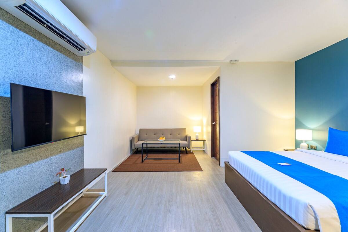 A hotel room with a bed, a sofa, a TV, and a desk.