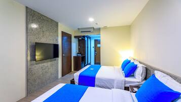 A hotel room with two beds, a flat-screen TV mounted on the wall, and a door leading to a hallway.