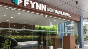 The exterior of the Fynn Boutique Hotel with a glass facade, a visible reception area, and potted plants. - Fynn Boutique Hotel (Bacoor City)