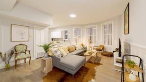 Un salon moderne avec un canapé d’angle gris, une table basse en bois et un tapis en peau de vache.