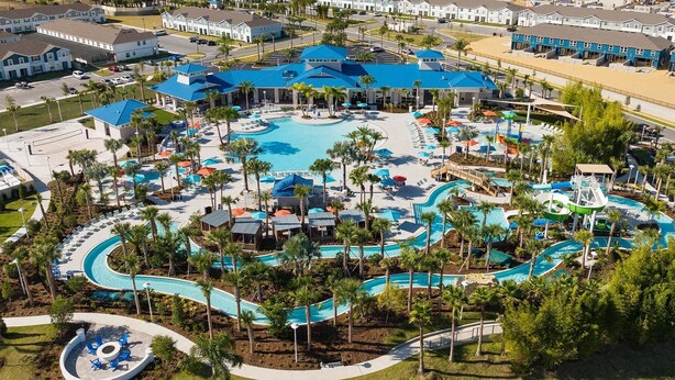 Vue aérienne d’un complexe hôtelier doté de plusieurs piscines, de palmiers et d’un grand bâtiment surmonté d’un toit bleu.