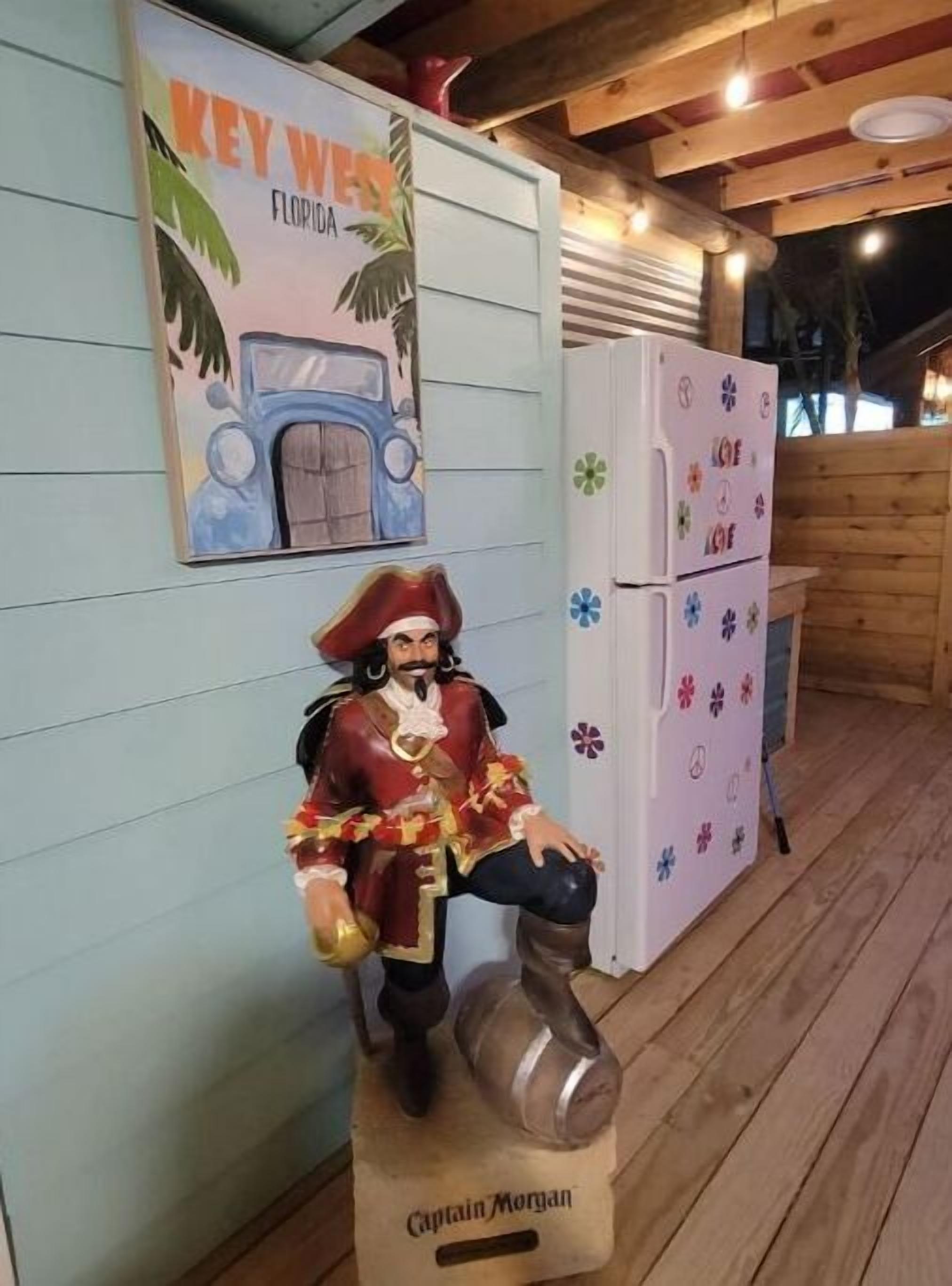 A wooden deck with a statue of a pirate, a refrigerator with colorful magnets, and a sign that reads "KEY WAY FLORIDA".