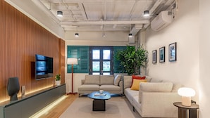 Una sala de estar moderna con un televisor de pantalla plana, un sofá, una mesa de centro y una planta en maceta.