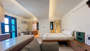 Una habitación de hotel moderna con sofá, cama, escritorio y kitchenette.