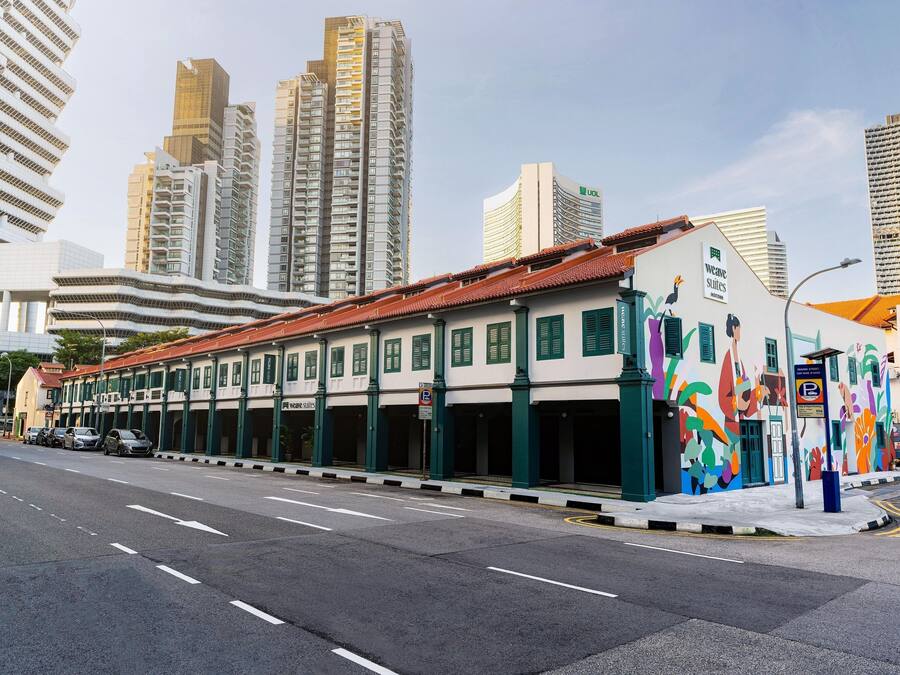 A street view with a building featuring a colorful mural, a parking sign, and tall modern buildings in the background.