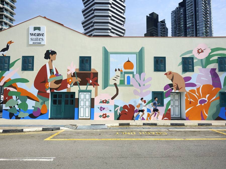 A building with a colorful mural featuring abstract figures and flora.