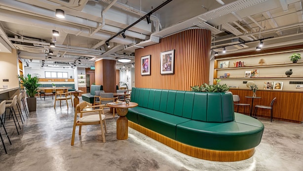 Un interior moderno con un sofá verde, mesas y sillas de madera.