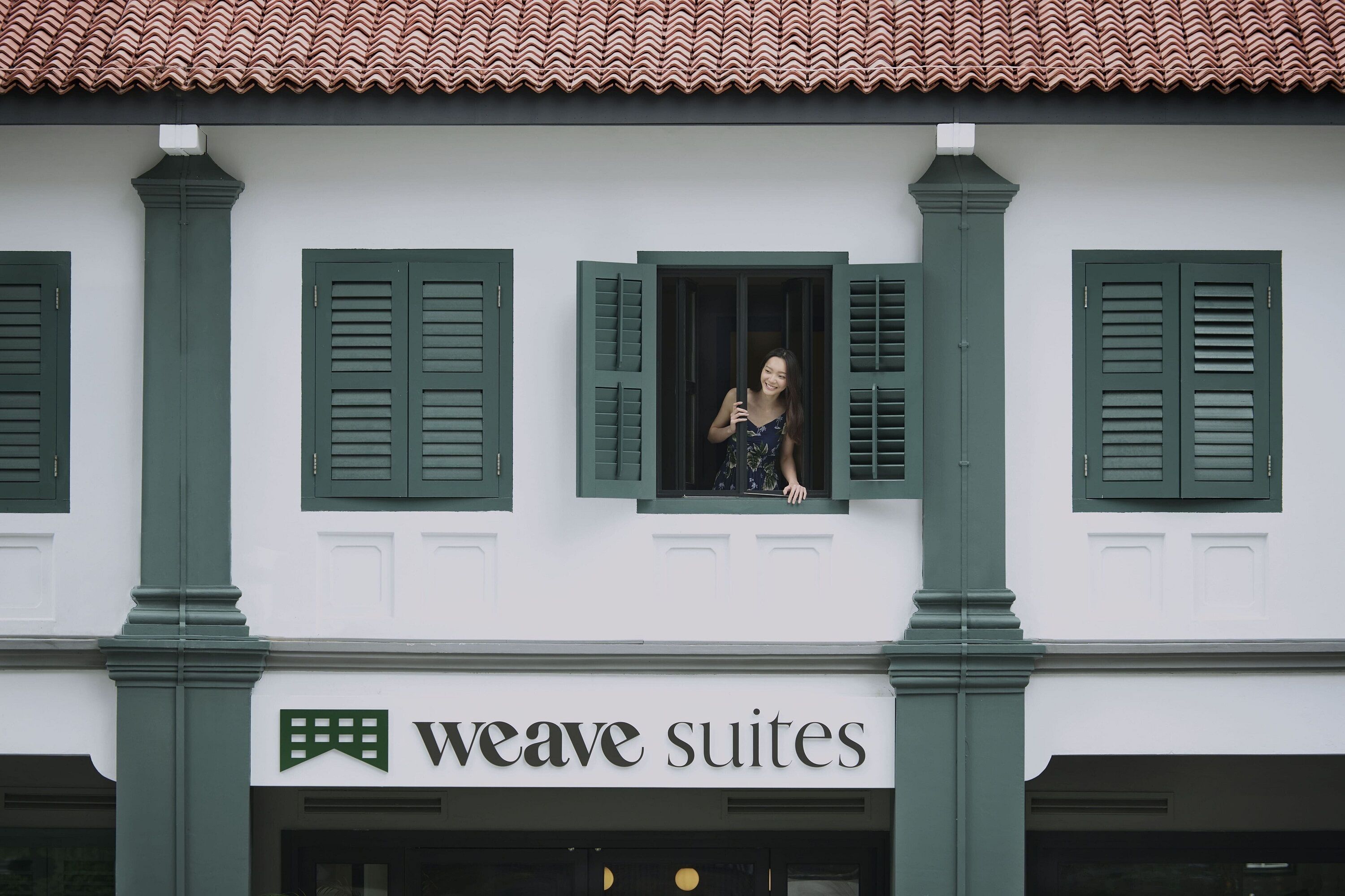 Un edificio con contraventanas verdes y un letrero que dice 'weave suites'.