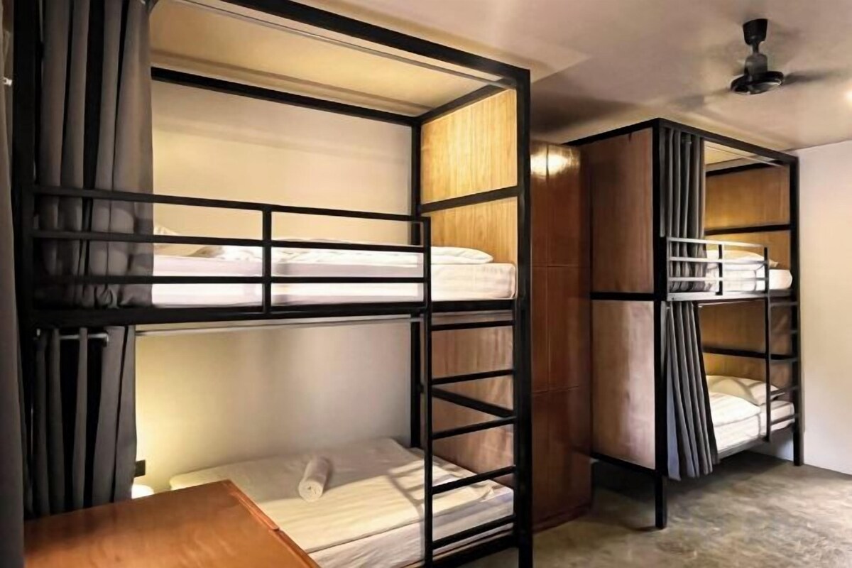 Habitación con literas, una mesa de madera y un ventilador de techo.