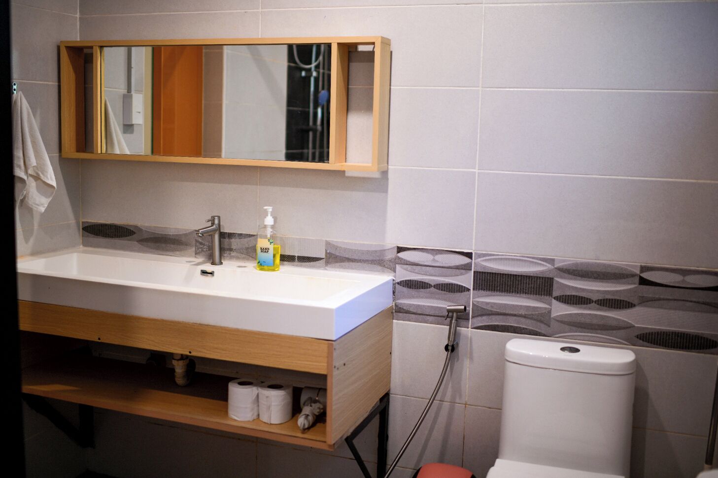 Une salle de bain avec un meuble-lavabo en bois, un miroir, un lavabo, des toilettes et une douche.