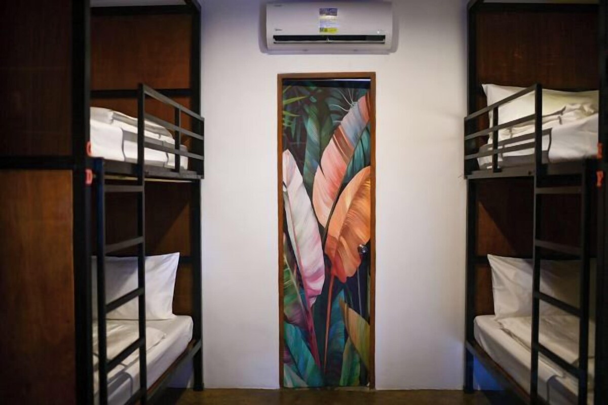 Una habitación con literas, una puerta con un diseño de hojas de colores y un equipo de aire acondicionado sobre la puerta.