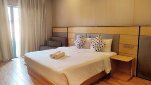 Una habitación de hotel con una cama grande, una mesita de noche y una silla.