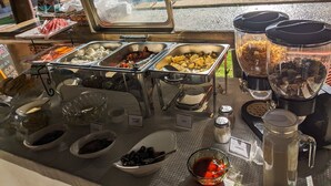 Montaje de bufé con diversos alimentos y una piscina al fondo.
