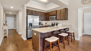 A kitchen with a central island, wooden cabinets, stainless steel appliances, and a clock on the wall.