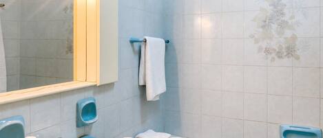 Un baño con un lavabo azul, un espejo, un perchero para toallas y una bañera.
